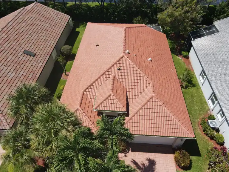 Overhead view of a red tile roof on a house beside a lawn and driveway in Boynton Beach, photographed July 2025