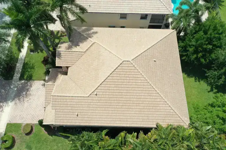 Vista aérea en ángulo de un techo de tejas planas color arena en una casa de una planta con piscina y palmeras detrás en Boynton Beach