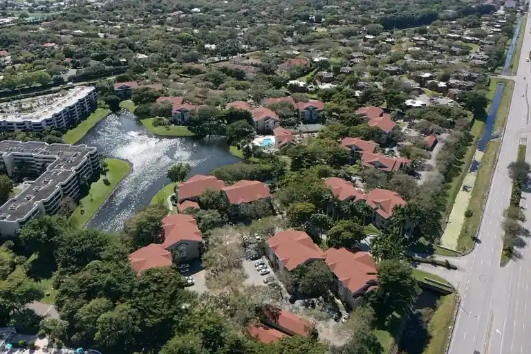 Aerial view of shingle roofs on a residential community beside a lake and road in Verano, Delray Beach