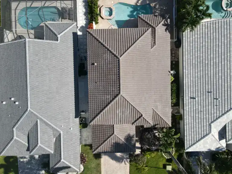 Overhead view of a finished brown tile roof between two houses, with a pool and circular spa behind in Delray Beach, completed August 2026