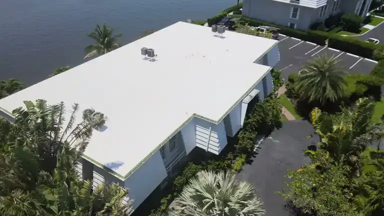 White flat roof on a two-story waterfront home with rooftop air units