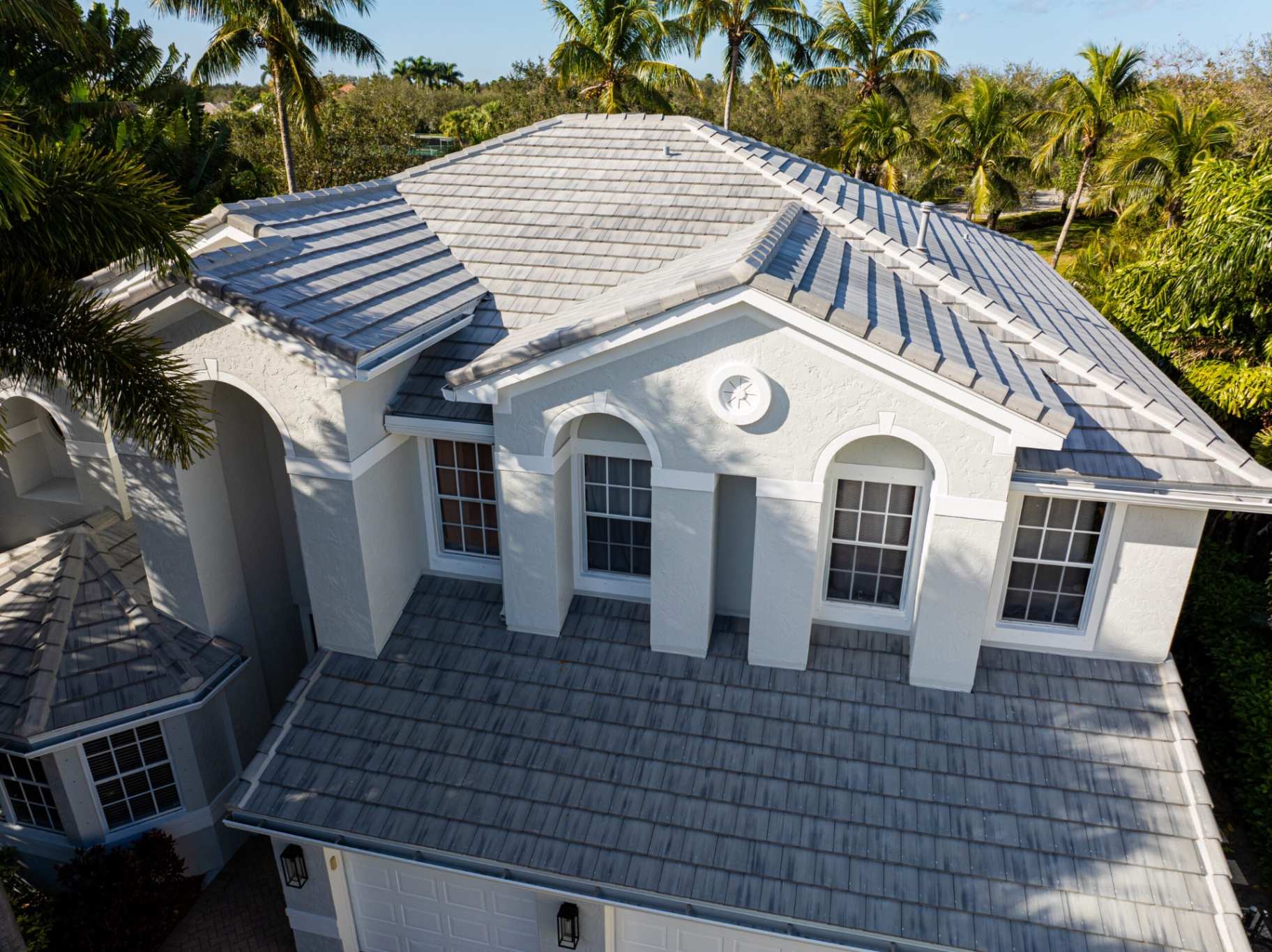 Gray flat tile roof on white stucco home aerial view
