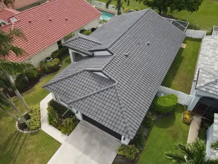 Dark gray tile roof on a single-story house with palms beside the driveway in Greenacres