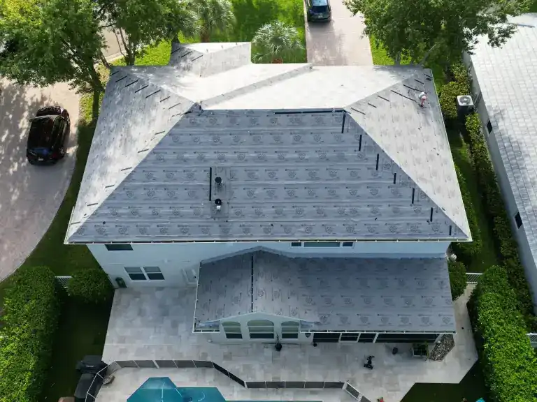 Drone view of a roof replacement in progress, with exposed printed underlayment above a white house and screened pool patio in Jupiter