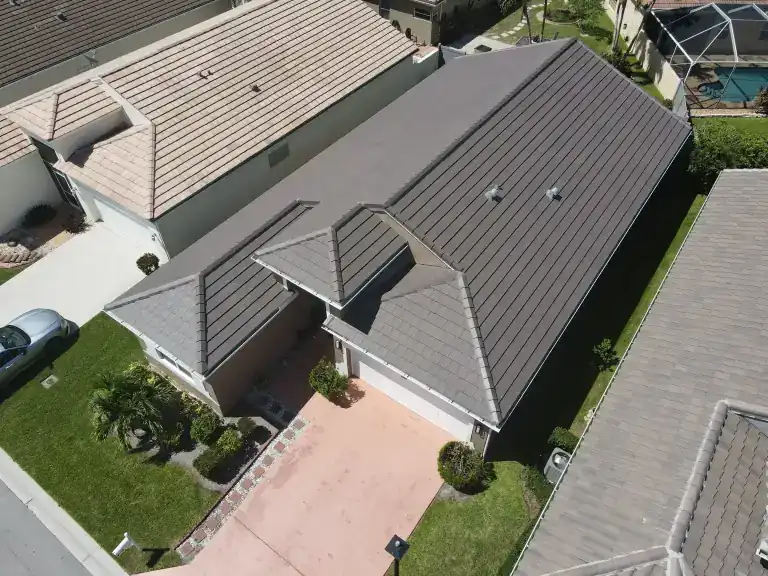 Dark tile roof on a single-story house between neighboring homes in Lake Worth Beach, photographed July 2025