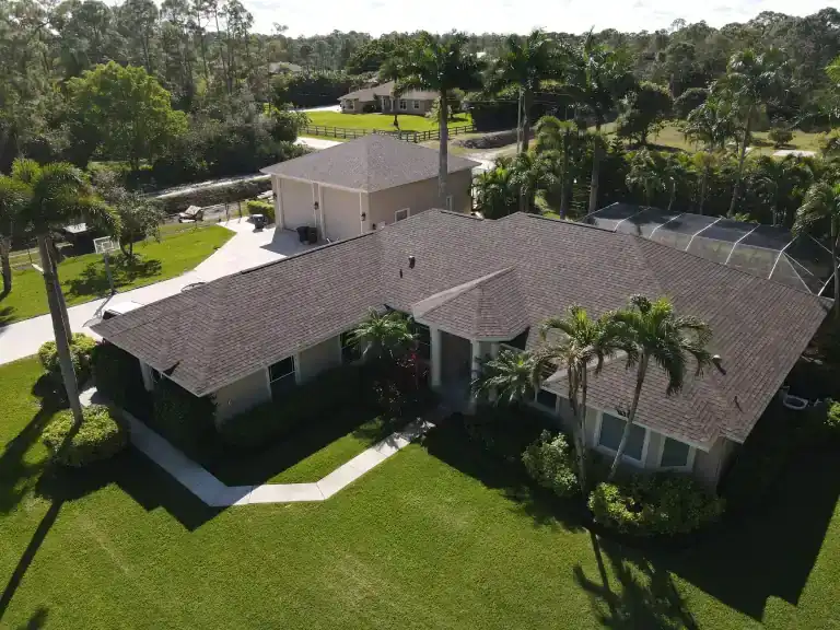 Techo de tejas asfálticas marrones de una casa con patio con mosquitero y palmeras en Loxahatchee, fotografiado en febrero de 2025