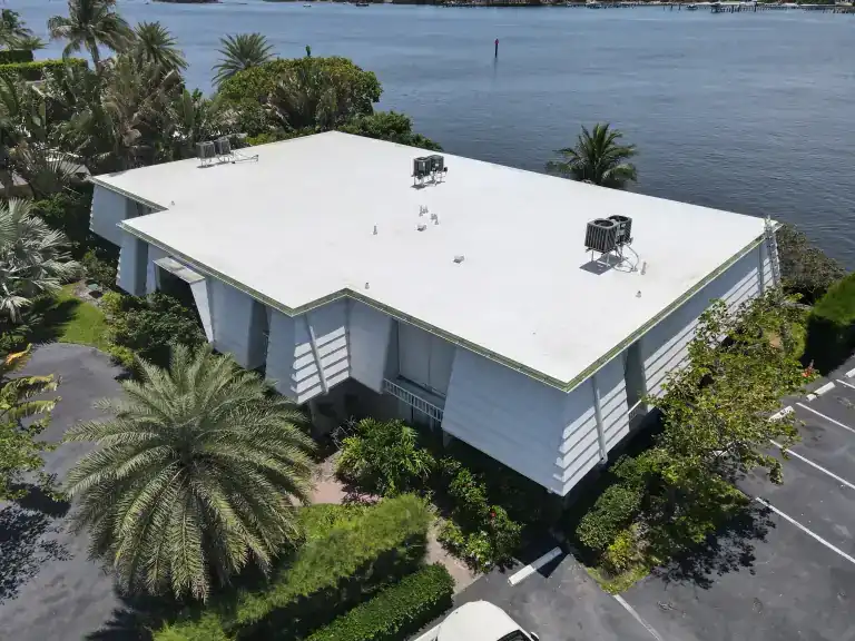 White flat roof on a low-rise waterfront building beside palms in Palm Beach, completed June 2026