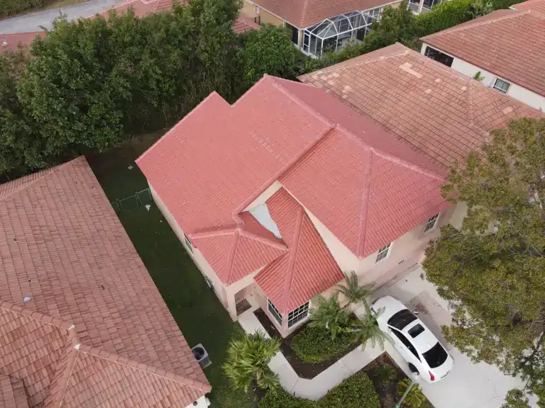 Red tile roof on a single-story house with a driveway and mature trees in Palm Beach Gardens, photographed December 2024