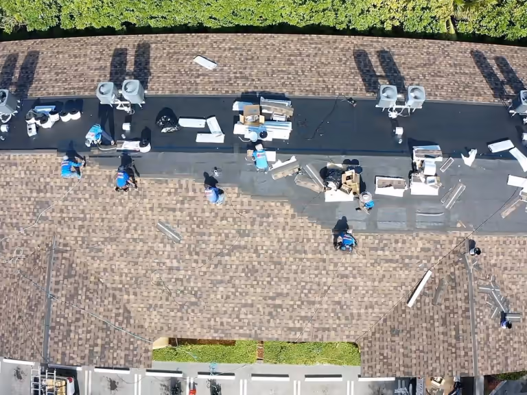 Shingle re-roof under way on a low-slope building with rooftop air units