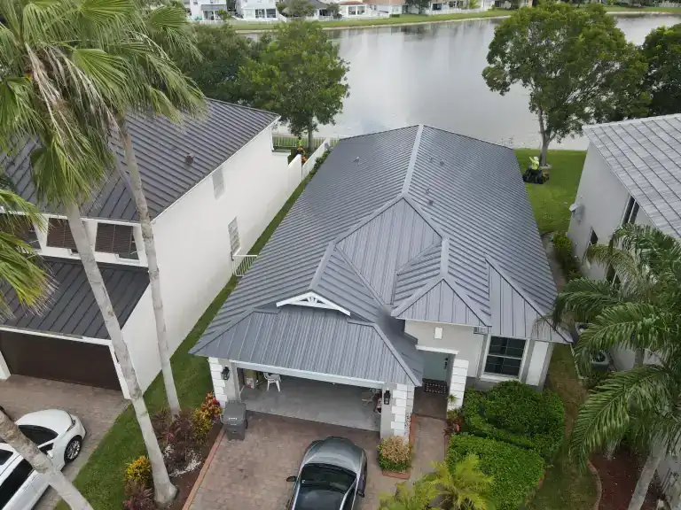 Gray metal roof on a lakeside house with palms and a driveway in Royal Palm Beach, photographed August 2025