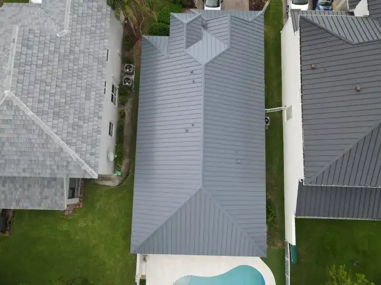 Overhead view of a gray metal roof on a house between neighboring homes in Royal Palm Beach, photographed August 2025