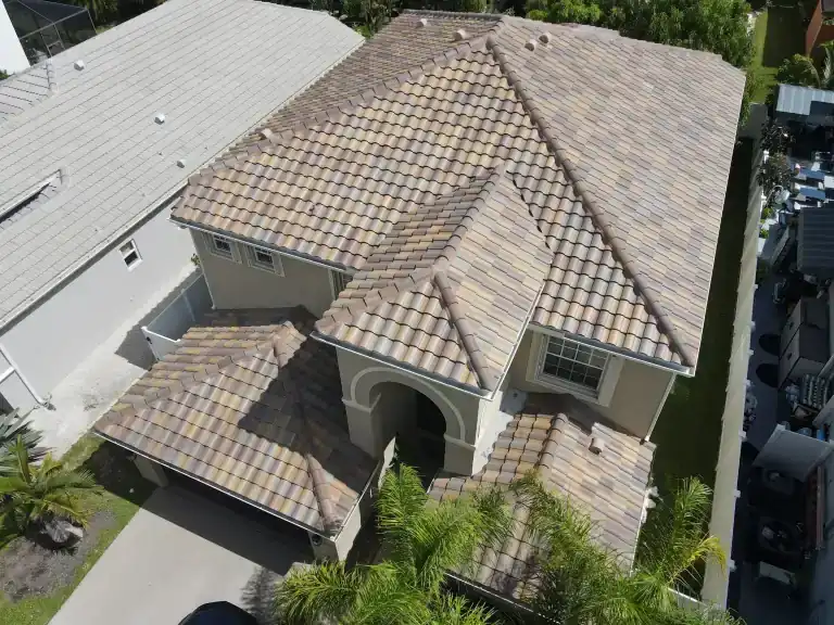 Techo de tejas color arena sobre una casa de dos pisos con entrada en arco, garaje y patio lateral estrecho en Royal Palm Beach, fotografiado en agosto de 2025
