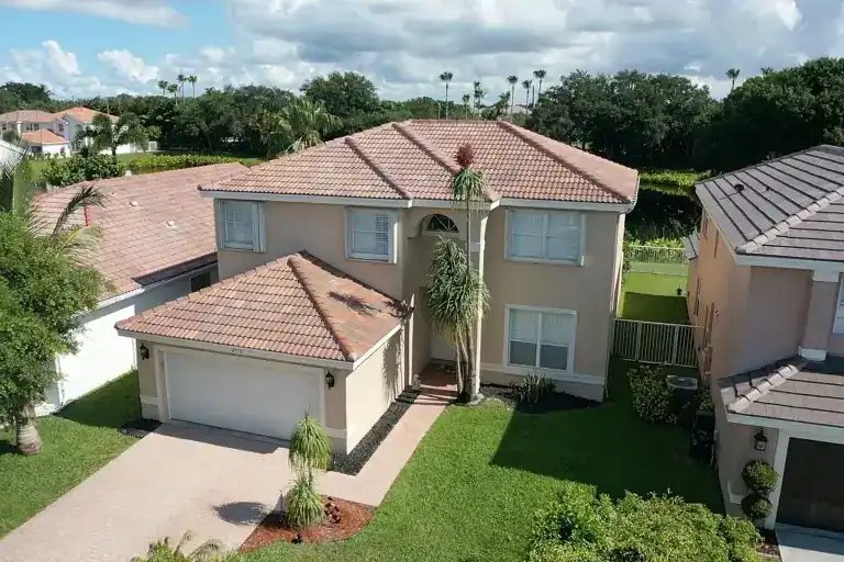 Tan tile roof on a two-story house with a garage and lawn in Royal Palm Beach