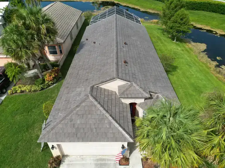Gray tile roof on a single-story house with a screened patio beside a pond in Wellington, photographed August 2024