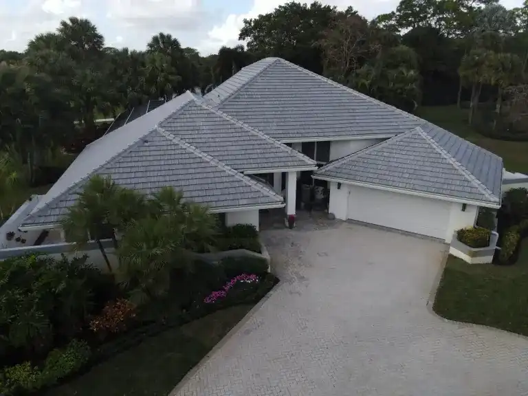 Dark gray tile roof on a single-story house with palms beside the driveway in West Palm Beach, photographed December 2024