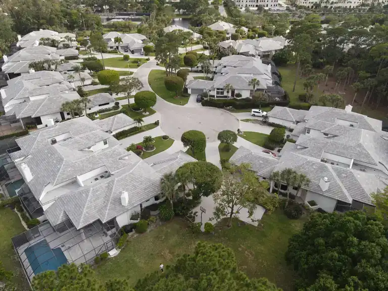 Light tile roofs on homes arranged around a landscaped cul-de-sac with mature trees