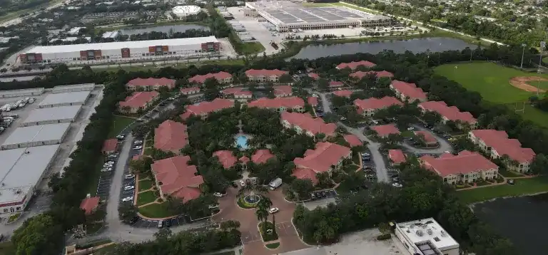 Techos de tejas rojas alrededor de patios arbolados junto a almacenes y una avenida en West Palm Beach